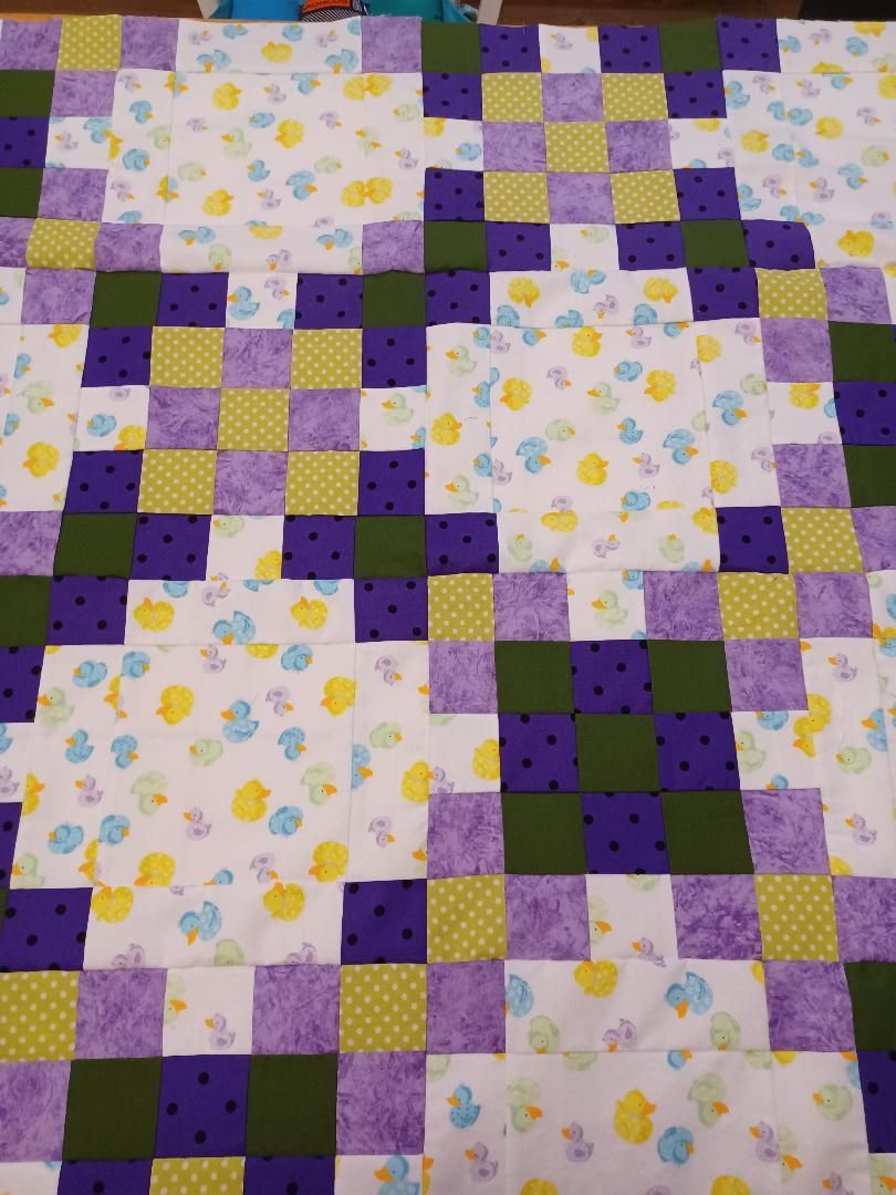 Purple, yellow, and green patchwork quilt with floral fabric squares.