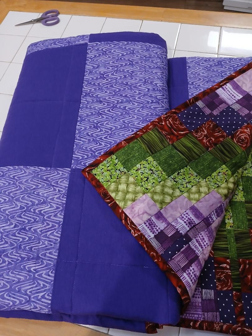 Folded purple and multicolored patterned fabric on a tiled floor