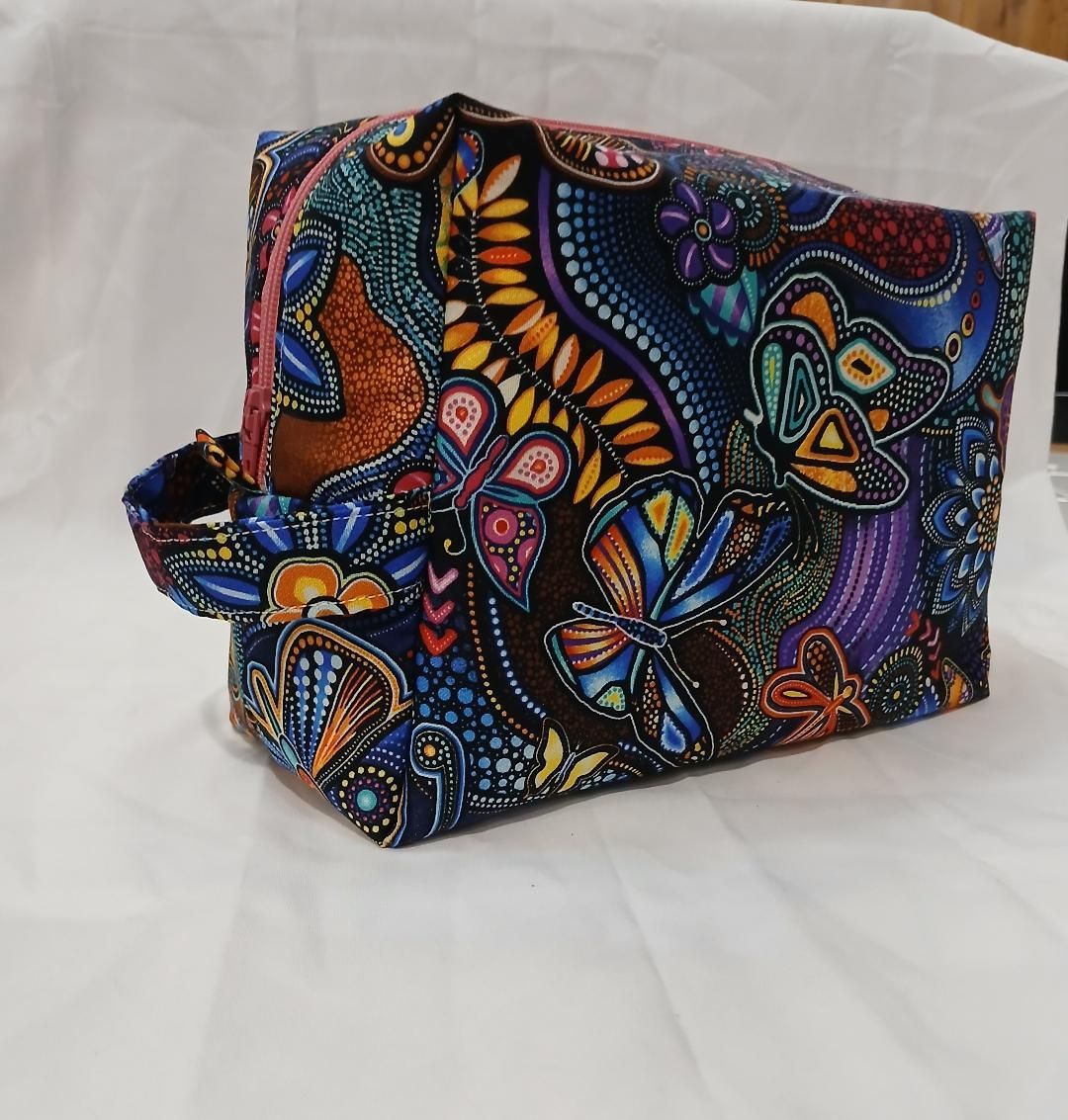 Colorful patterned fabric bag with a zipper, shown on a white surface.