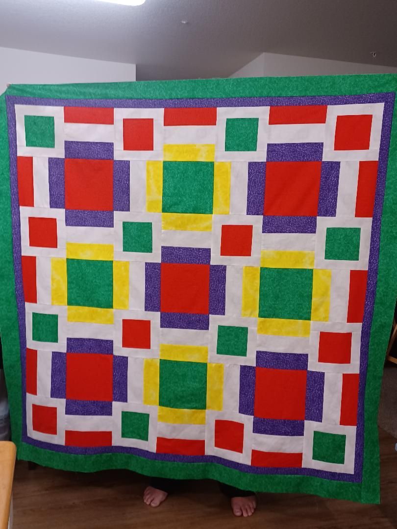Colorful geometric quilt with red, green, yellow, and blue squares and borders
