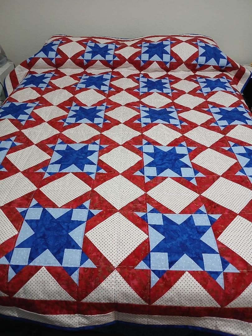 Red, white, and blue star-pattern quilt spread over a bed