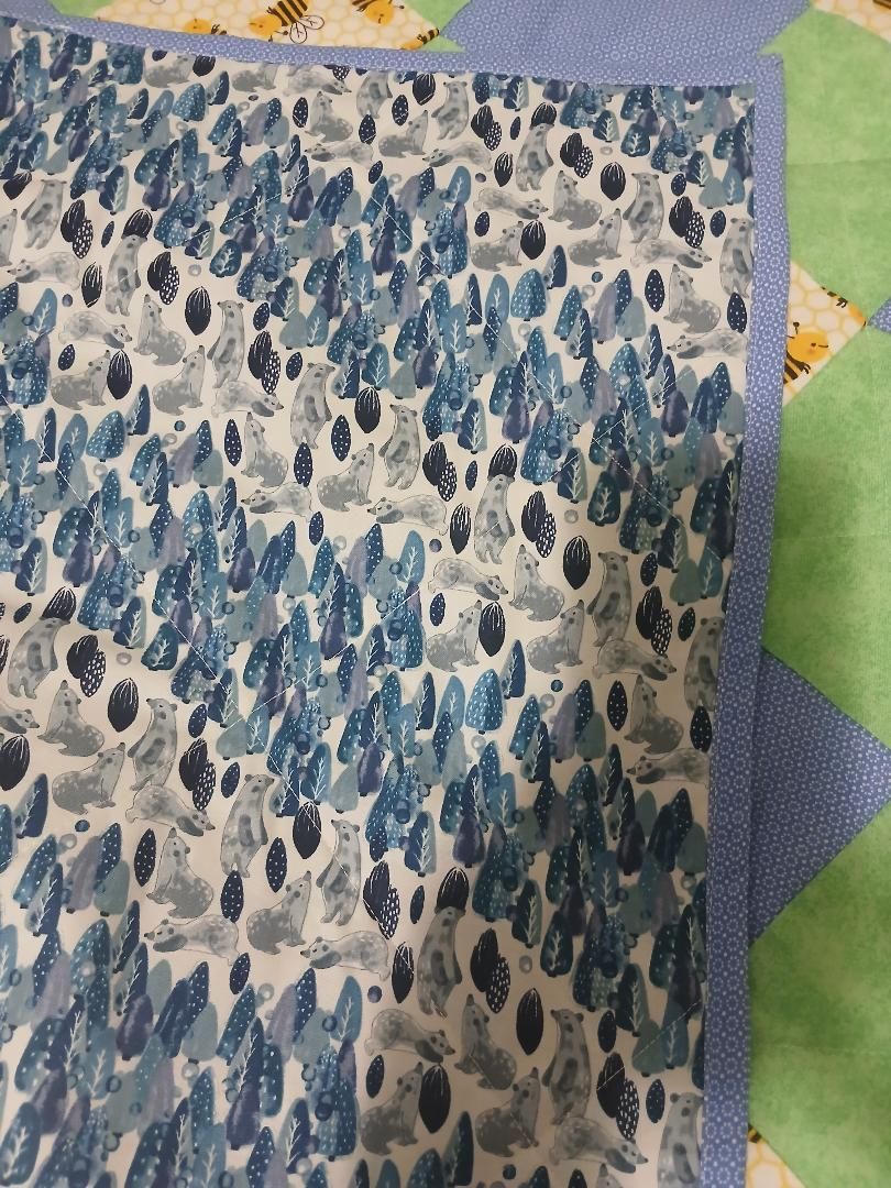 Blue-gray patterned quilt fabric with a purple border on a green surface