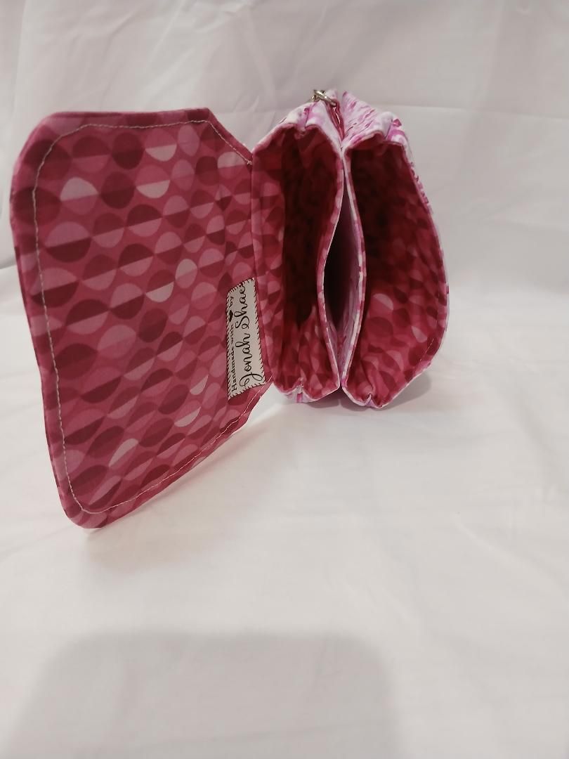 Pink patterned fabric folded item with a label, shown on a white background