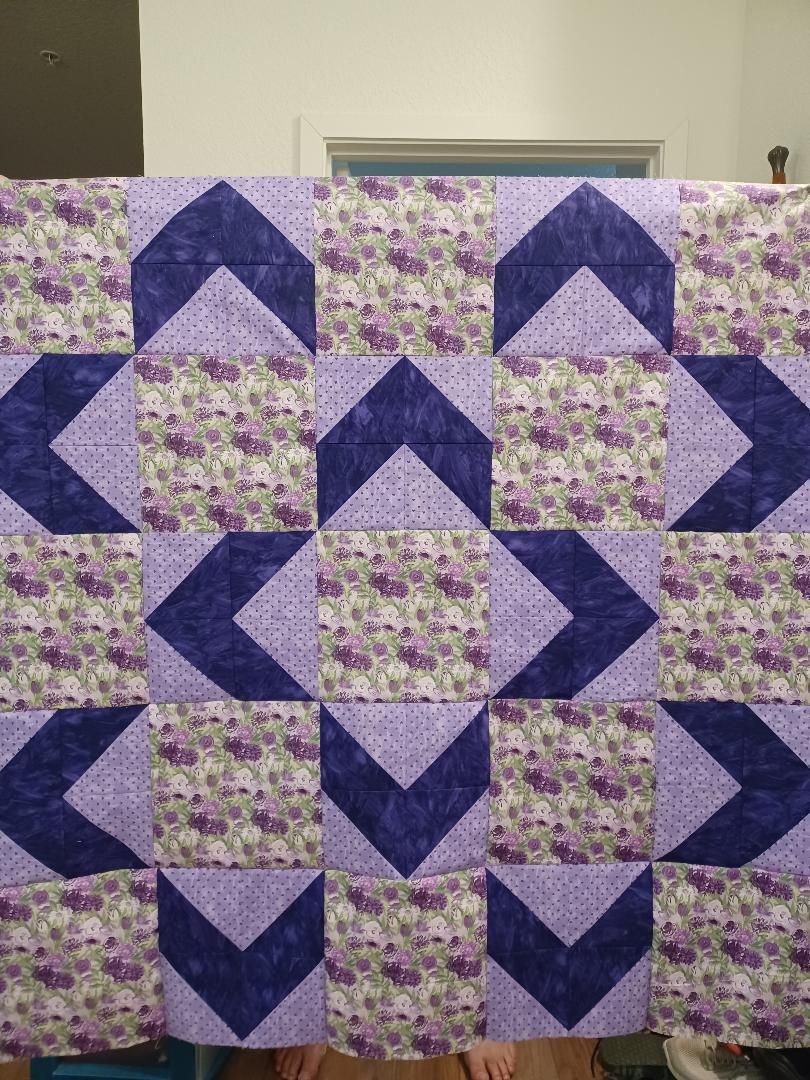 Purple and floral patchwork quilt with chevron blocks in a repeating geometric pattern