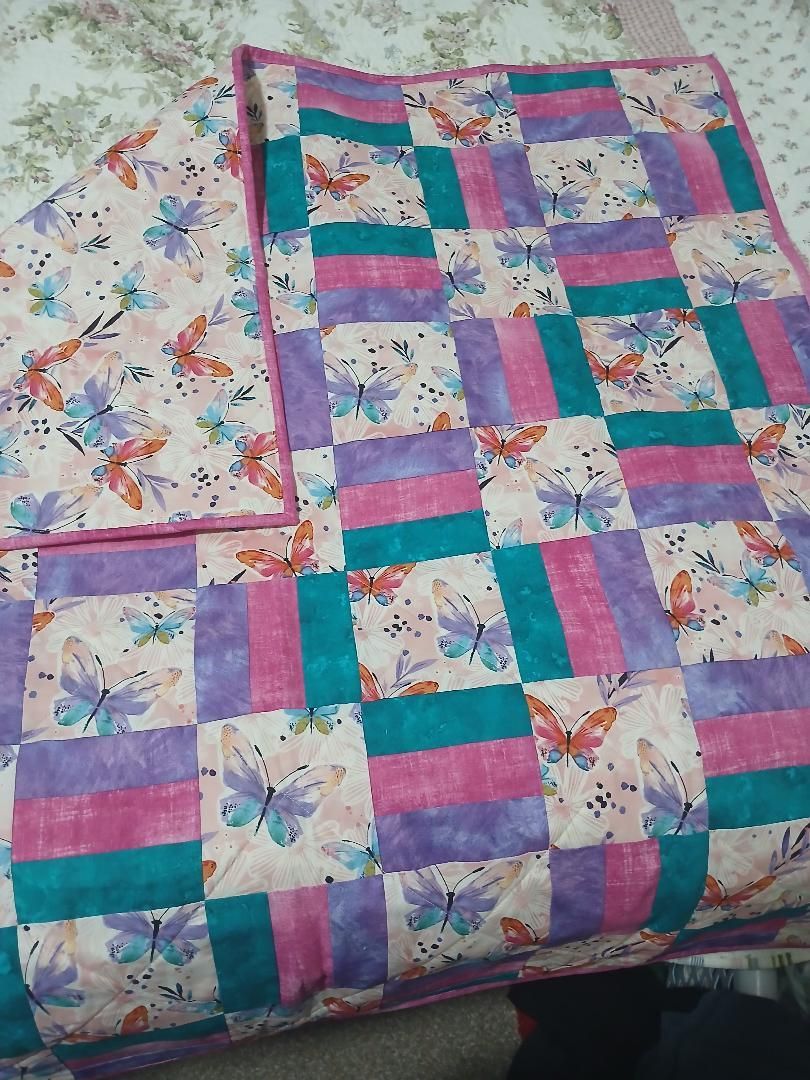 Colorful patchwork quilt in pink, teal, purple, and floral patterns on a bed.