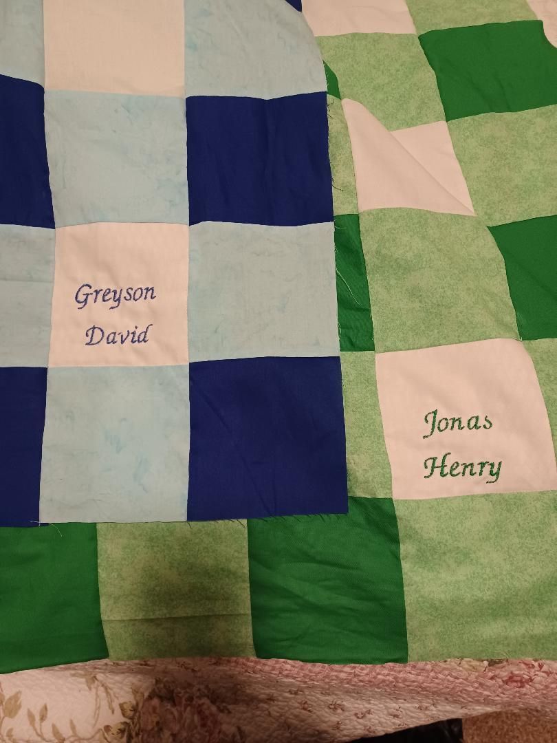 Patchwork quilt in blue, green, and cream with two labeled squares: “Gregory David” and “Jonas Henry.”