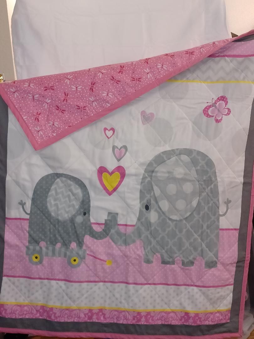 Pink-and-gray elephant blanket with hearts and butterflies hanging on a wall