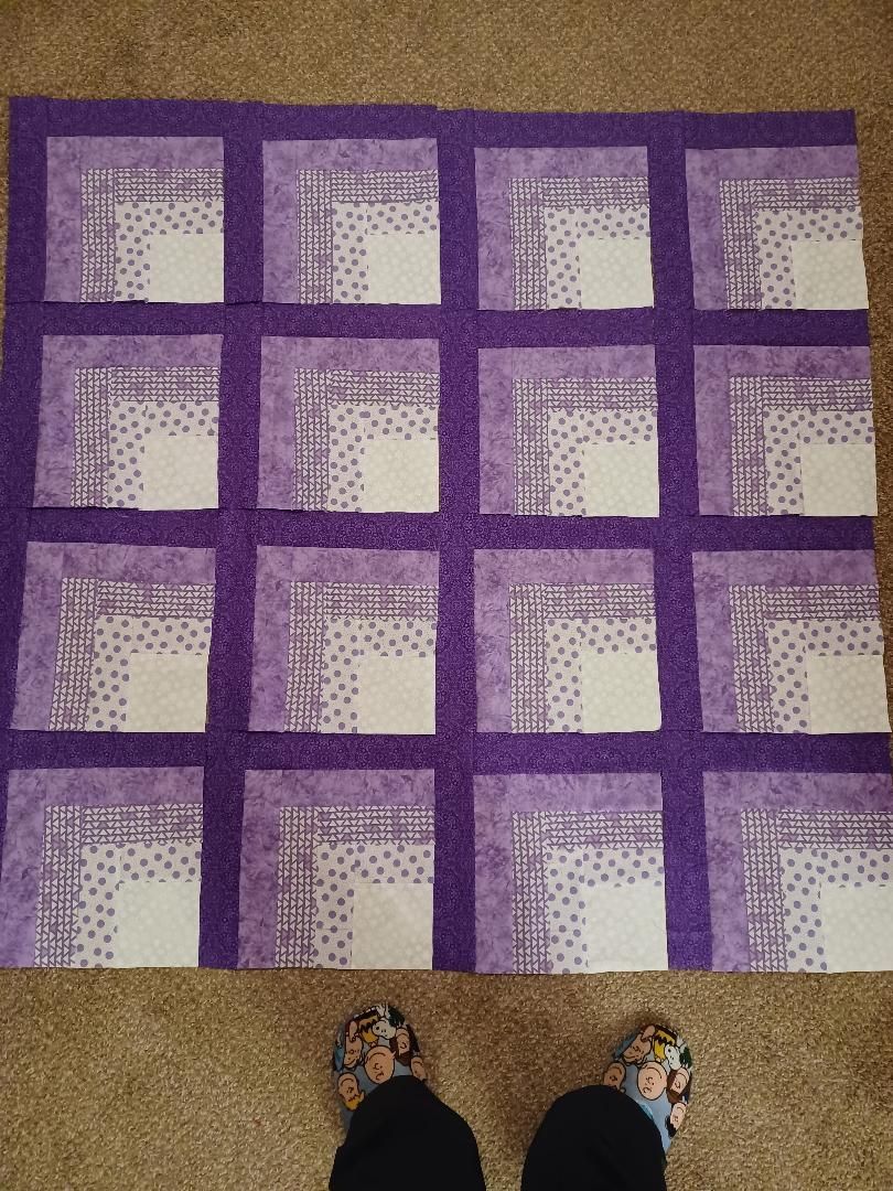 Purple and white checkered rug on a beige floor, with two feet visible at the bottom edge.