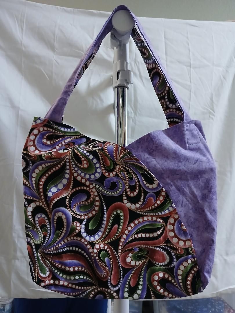 Colorful paisley tote bag with purple straps hanging on a chair back