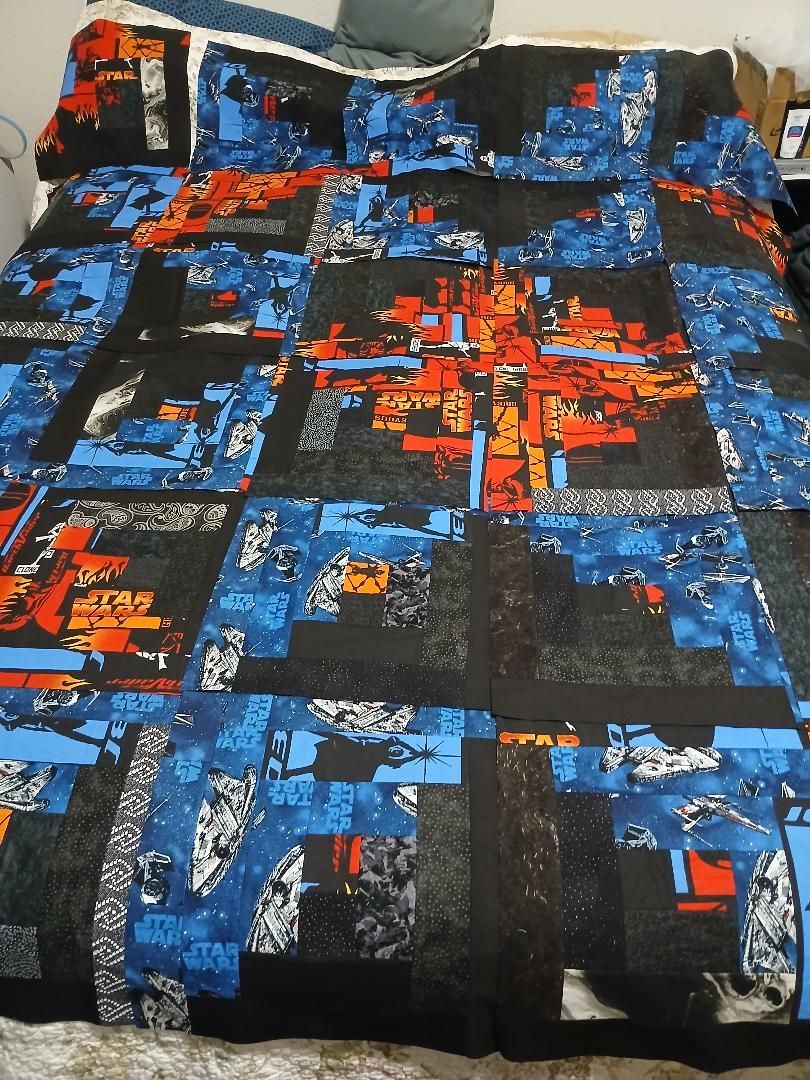 Blue, black, and red patterned bedspread with abstract city-style graphics on a bed