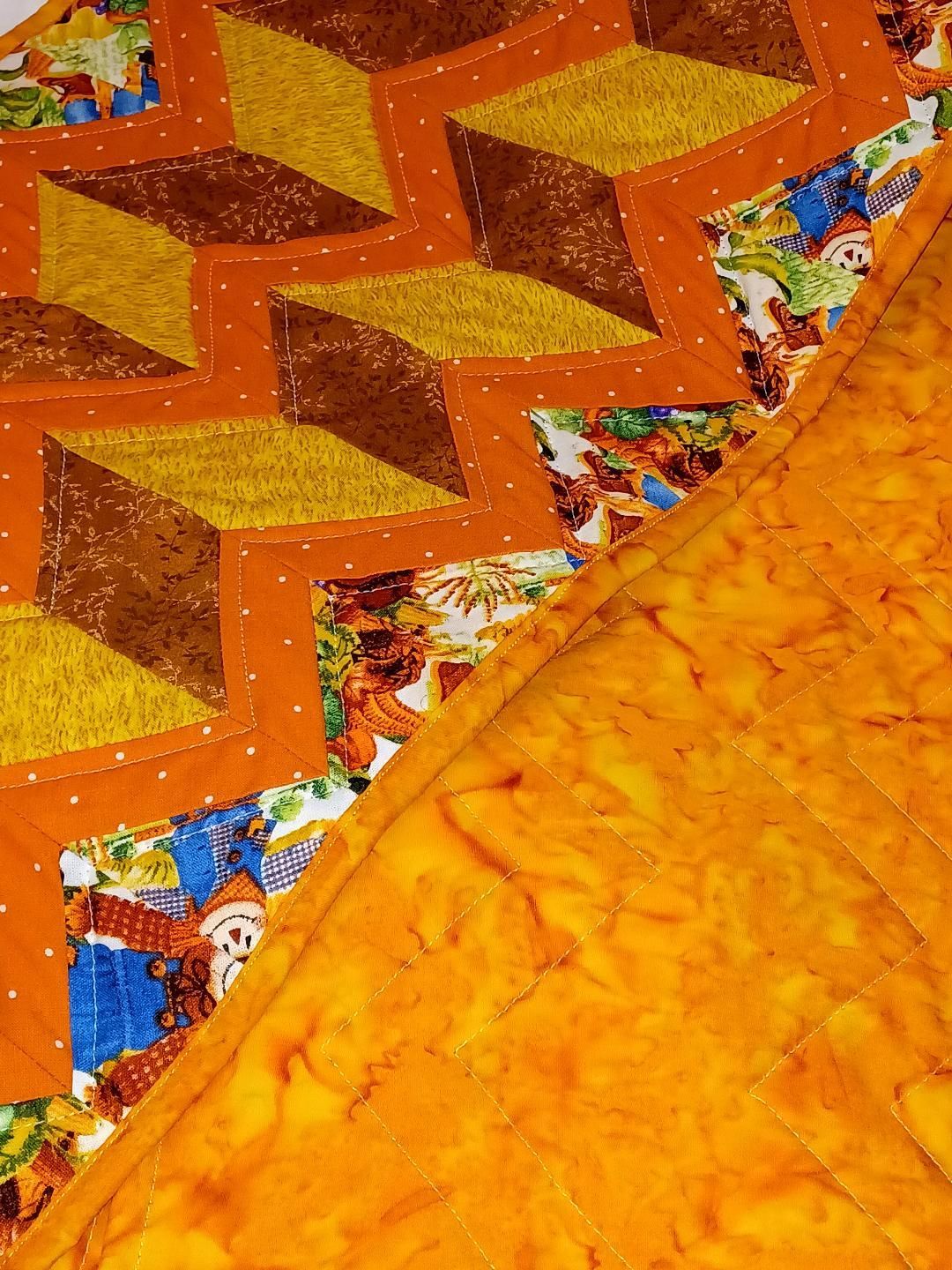 Orange quilt with zigzag patterned fabric and textured stitching details