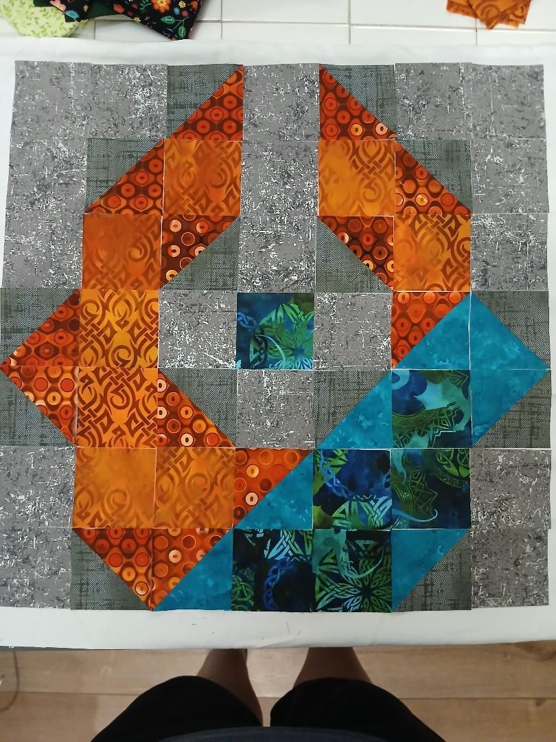 Colorful patchwork quilt with orange, blue, and gray geometric spirals on a table