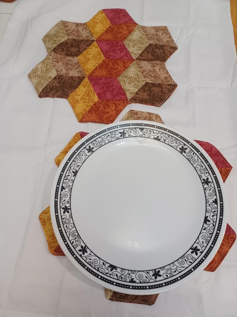 White plate on a colorful woven trivet, with another trivet partially visible below on a white background
