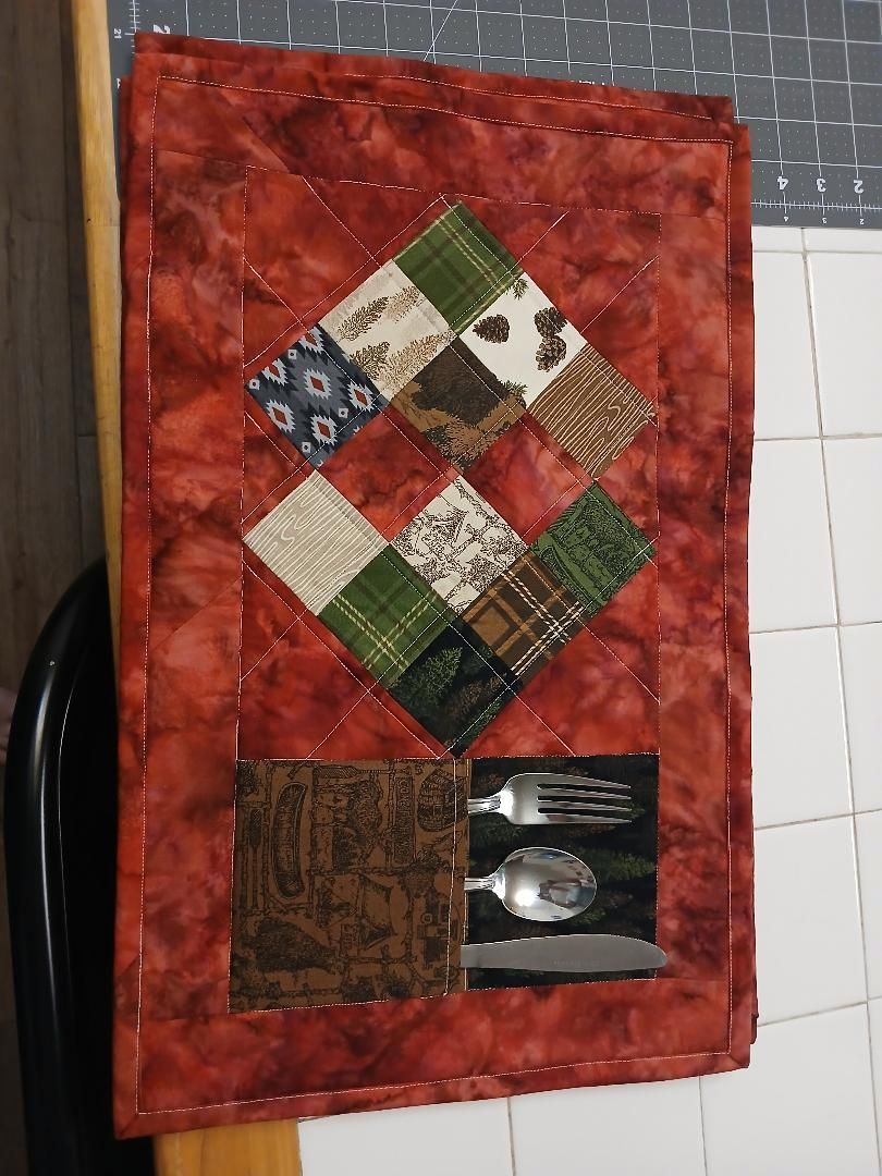 Decorative quilt with red border and multicolored patchwork squares, including two darker blocks near the bottom