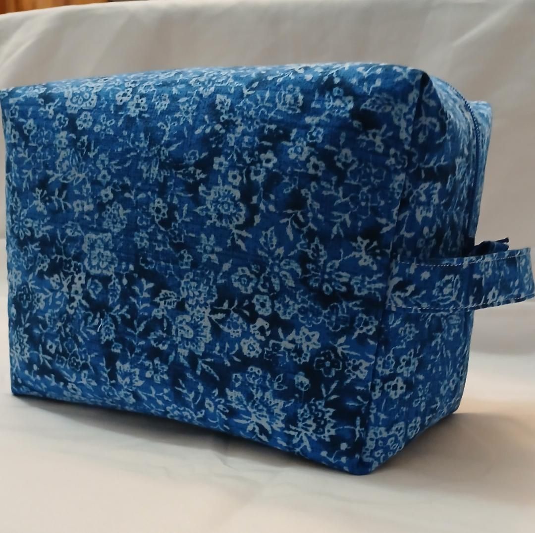 Blue floral fabric zip bag with a side handle on a white surface
