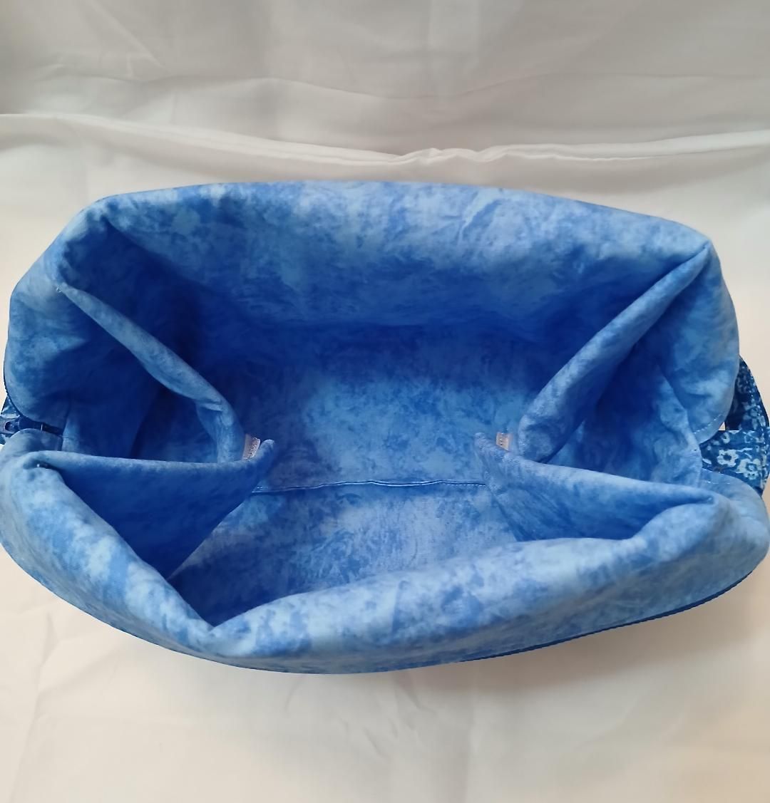 Blue plush pet bed with raised sides, sitting on a white surface