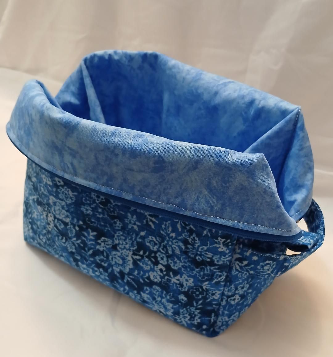 Blue fabric storage basket with a floral exterior and folded light-blue lining