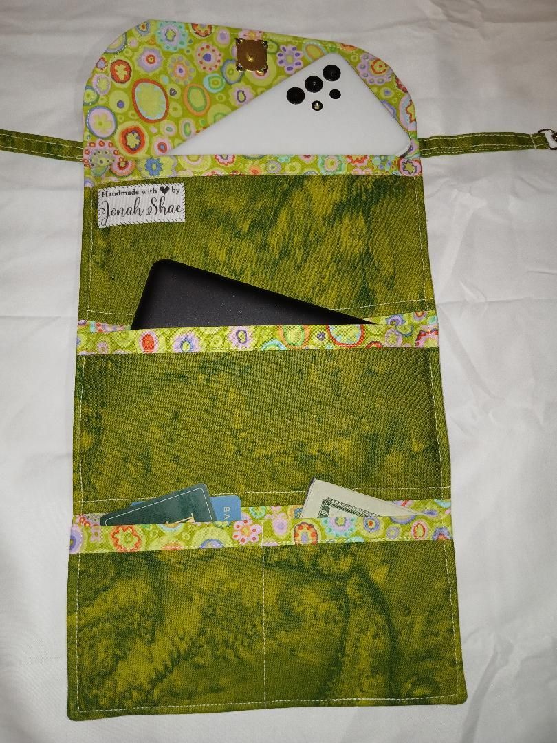 Green handmade fabric organizer with patterned flap and open pockets holding papers and a black object
