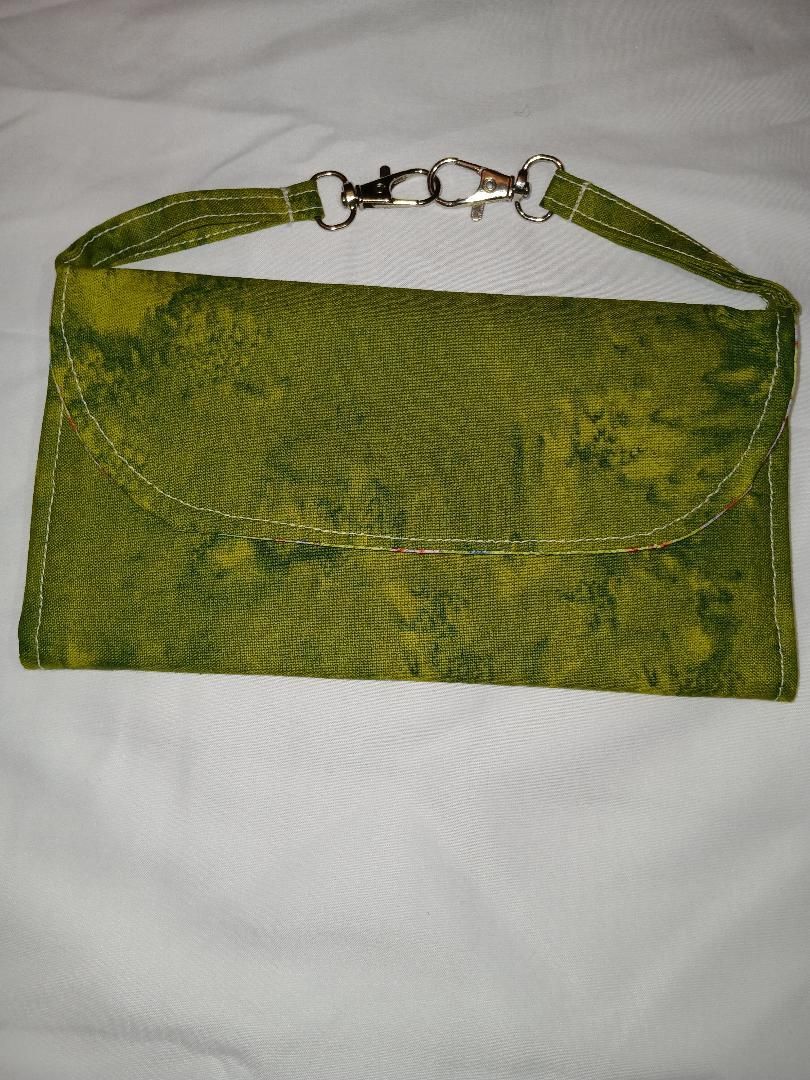 Green textured clutch purse with a chain strap on a white background