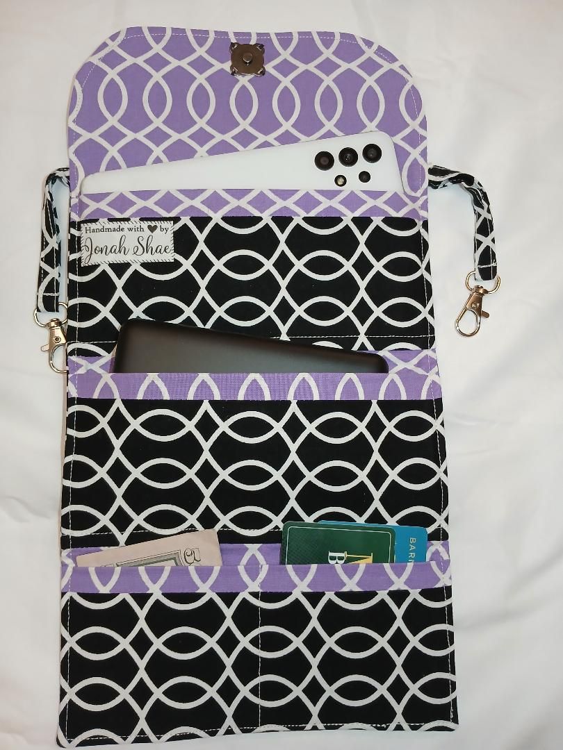 Purple and black patterned organizer pouch with pockets and a strap on a white background