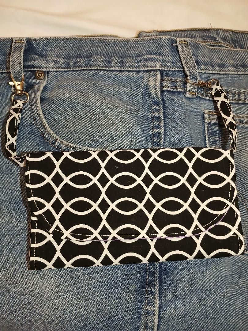 Black-and-white patterned purse hanging from the waistband of blue jeans