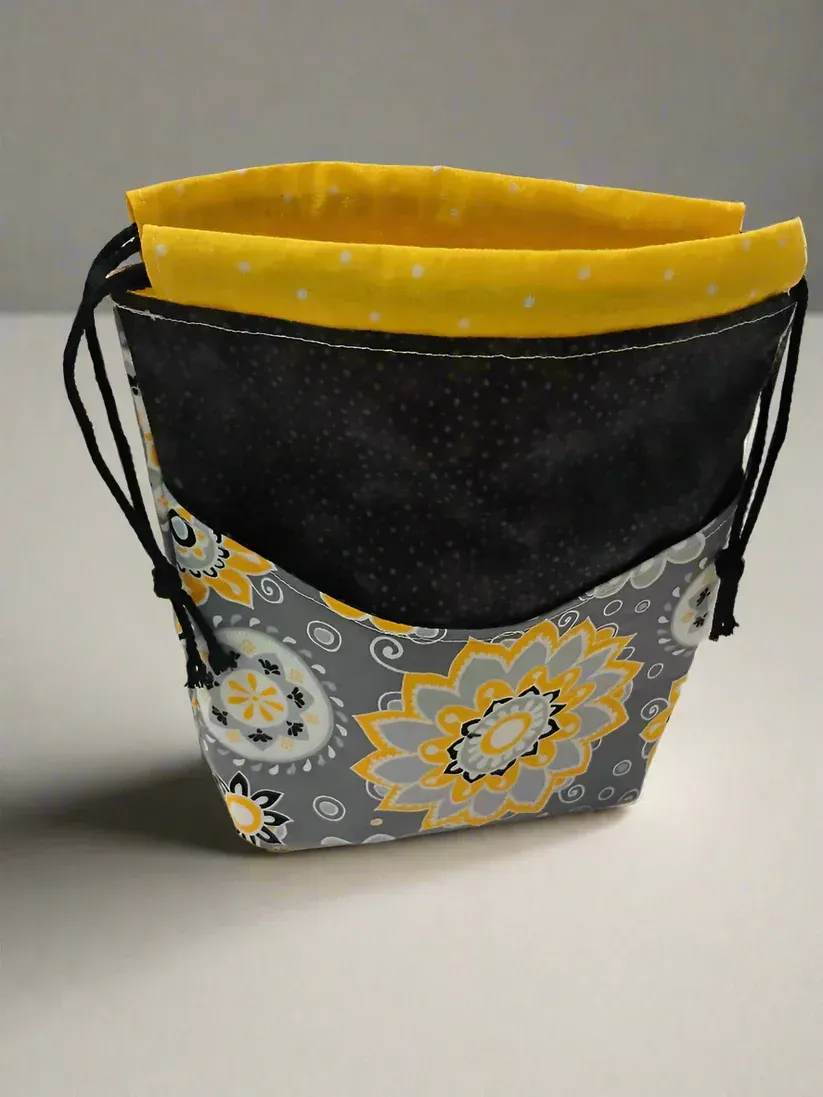 Small fabric tote bag with black, gray floral pattern and bright yellow lining on a white background