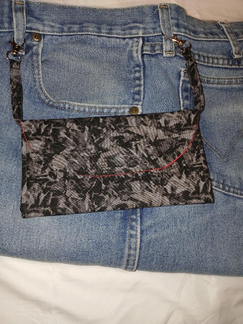 Blue jeans with a dark patterned patch sewn over a hole near the back pocket.