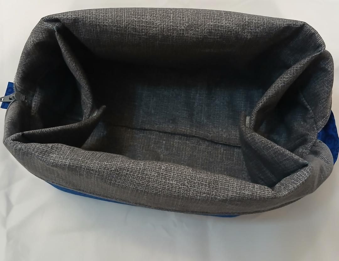 Open gray fabric tote or basket with blue trim, viewed from above on a white surface