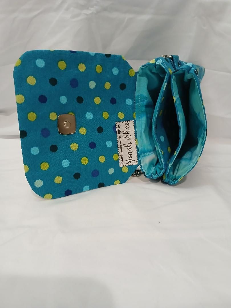 Turquoise polka-dot pouch with a black clasp, opened to show a matching blue interior.