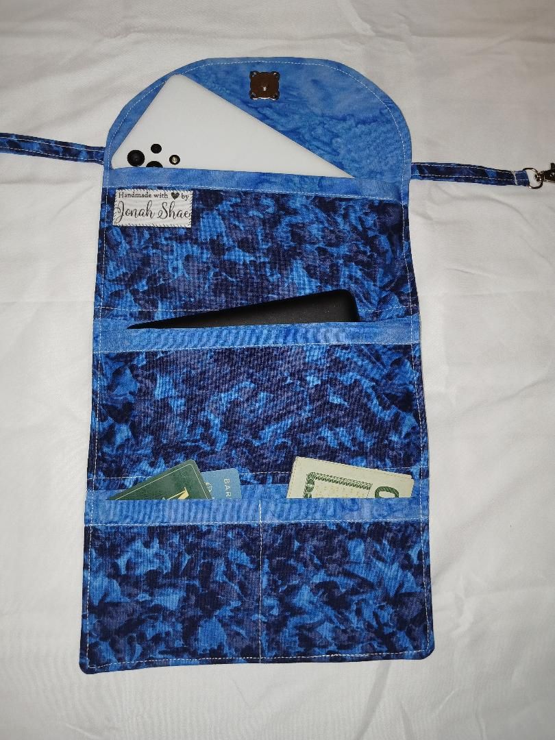 Blue fabric hanging organizer with pockets, a zipper flap, and a small orange patch on top.