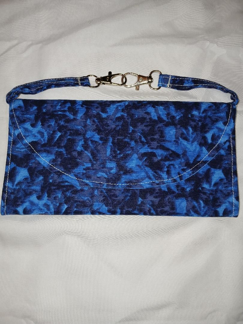 Blue patterned clutch purse with a beaded strap on a white fabric background