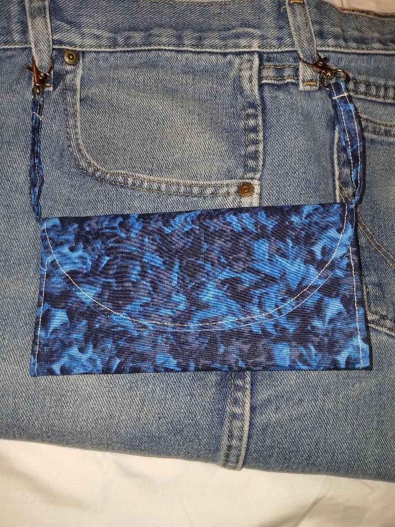 Close-up of a denim pocket with a blue patterned fabric patch sewn on the lower half