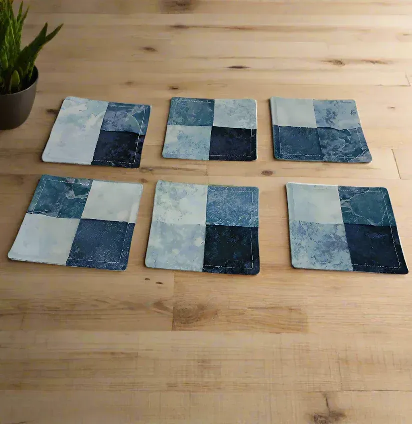 Six blue-and-white patchwork coasters arranged in two rows on a wooden table.