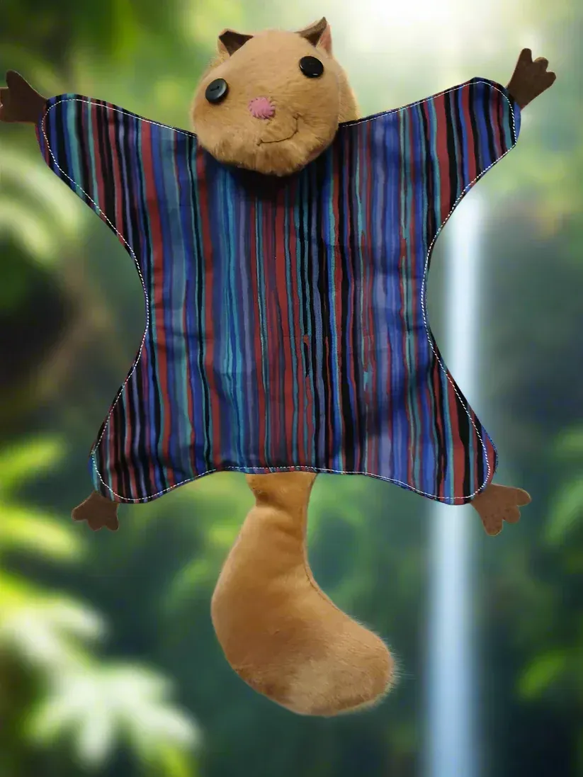 A plush squirrel-like toy in a blue striped shirt with arms raised against a blurred green outdoor background.