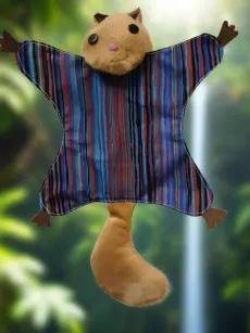 Plush cat puppet with striped shirt and curled tail against a blurred green outdoor background