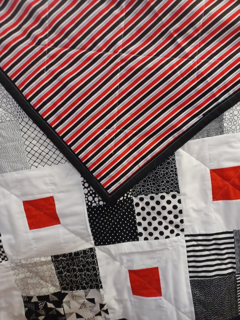 Patchwork quilt squares with red, black, white, and striped patterns