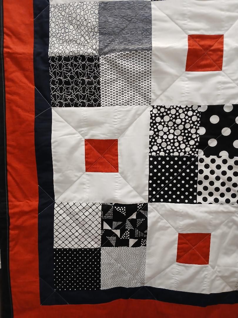 Black, white, and red patchwork quilt with patterned fabric squares and border stripes.