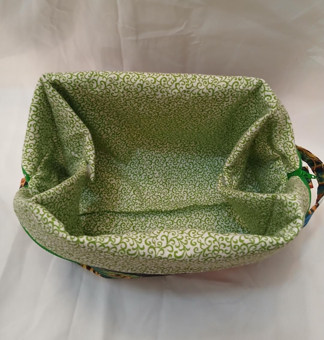 Green fabric basket with patterned lining and raised sides, viewed from above