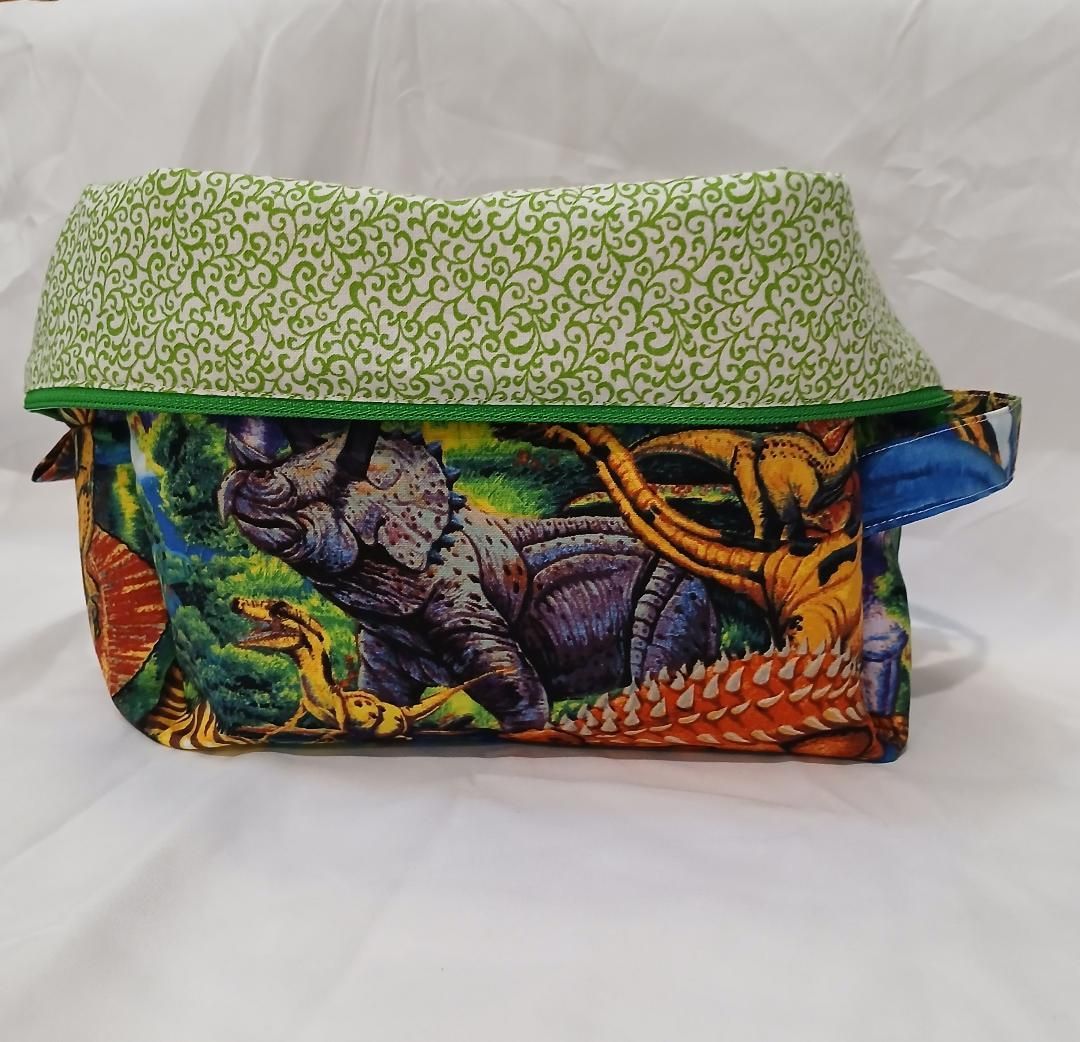 Colorful quilted fabric pouch with green patterned flap on a white background