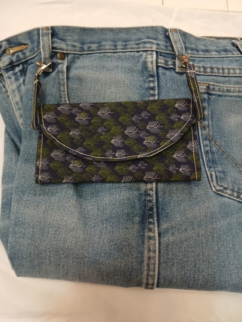 Small floral pocket sewn onto the back of faded blue denim jeans