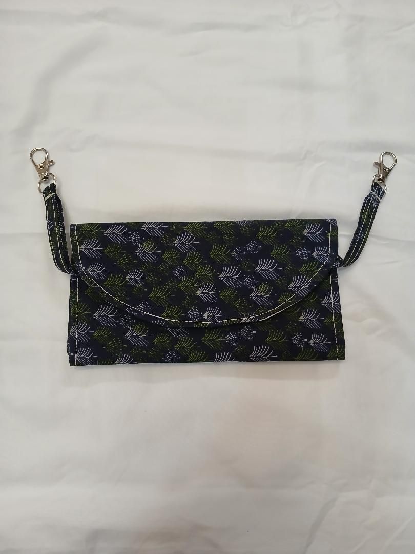 Small black floral clutch bag with chain strap on a light background