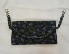 Black floral clutch purse with chain straps on a white background