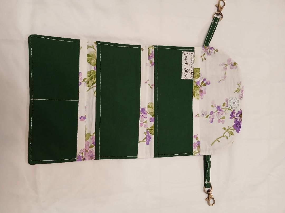 Green floral fabric craft with three dark green panels and a floral pocket, shown flat on a light background