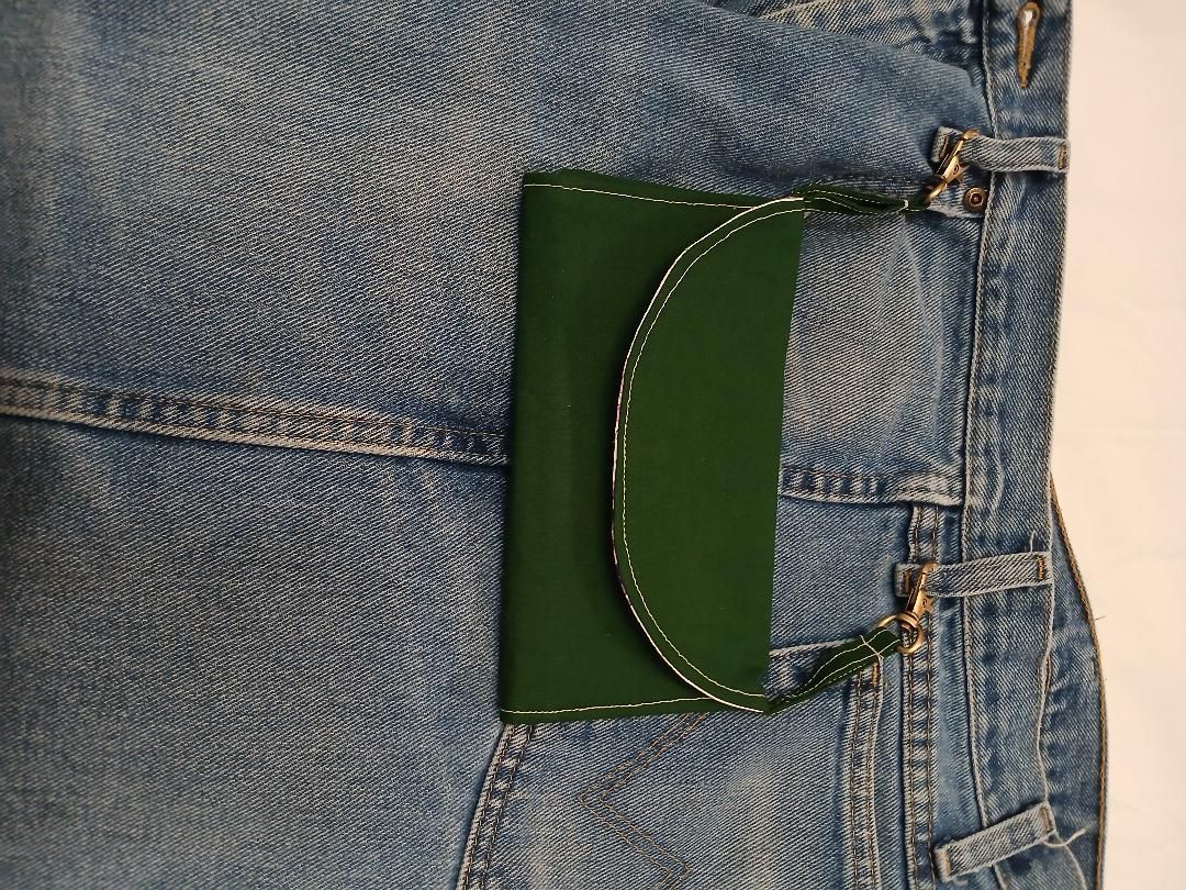 Close-up of blue denim jeans with a dark green card holder in the back pocket