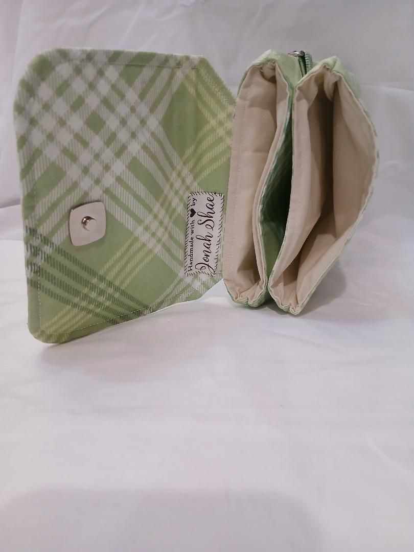 Green plaid fabric pouch with button flap, open to show beige interior and compartments