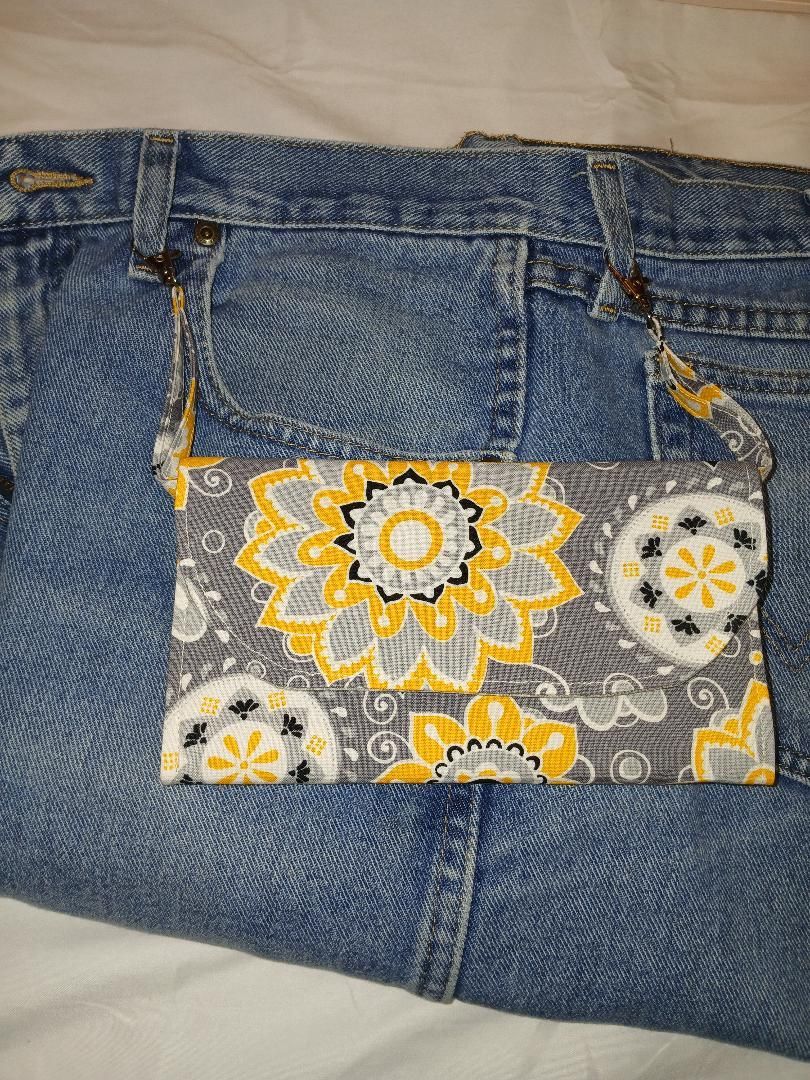 Denim jeans with a floral-patterned patch pocket in yellow, white, and gray