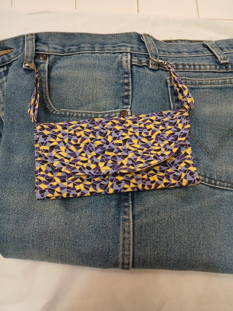 Folded blue jeans with a purple and yellow patterned fabric patch sewn across the back pocket area