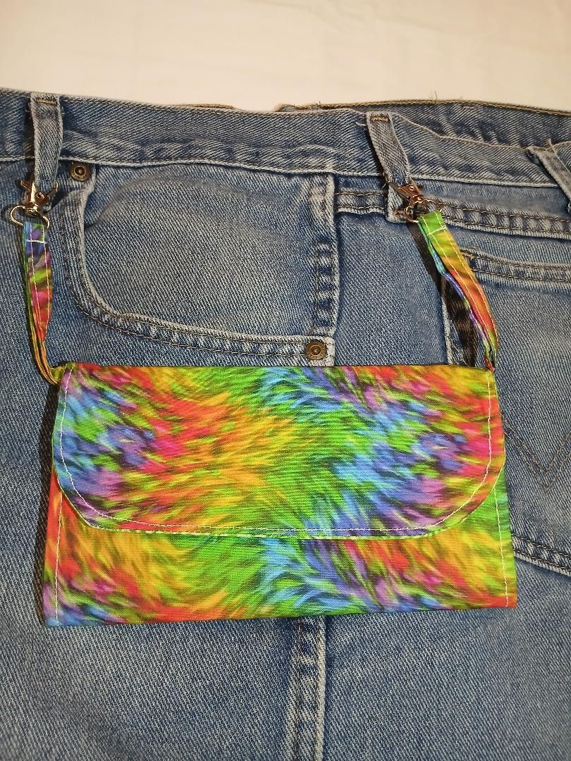 Rainbow tie-dye purse hanging on blue jeans pocket with a multicolored strap