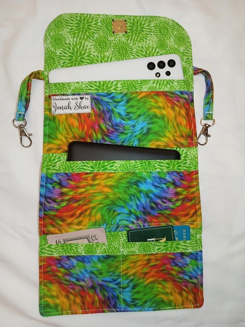 Colorful tie-dye crossbody bag with zipper pockets and a rainbow pattern on a white background
