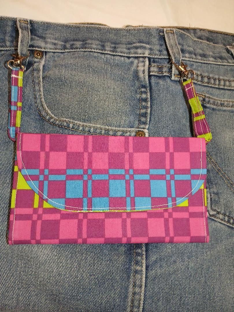 Pink and blue patterned purse hanging against blue denim jeans